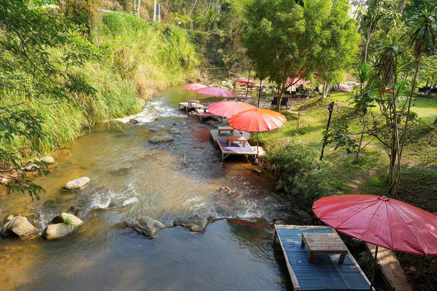 Rafts with red umbrellas in a clear stream, riverside restaurant in Mae Rim, Chiang Mai